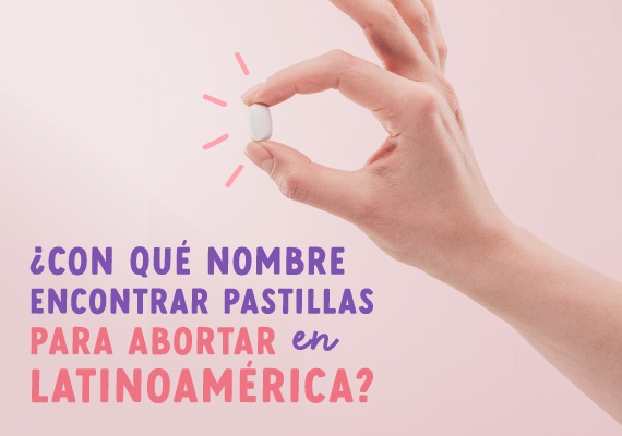 Mano sobre fondo rosa sosteniendo una pastilla abortiva